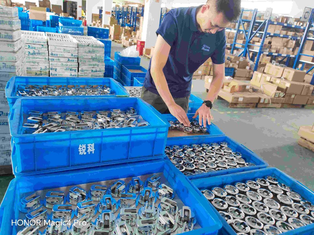 Reaking quality control technician inspecting polished industrial cabinet lock components in blue Reacoo bins at Shengzhou factory